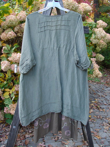 Barclay Hemp Silk Triangular Two Tier Dress Garden Soft Moss Rock Size 2 displayed on a rack, showcasing its unique V-shaped neckline, pinched accents, and varying hemline.