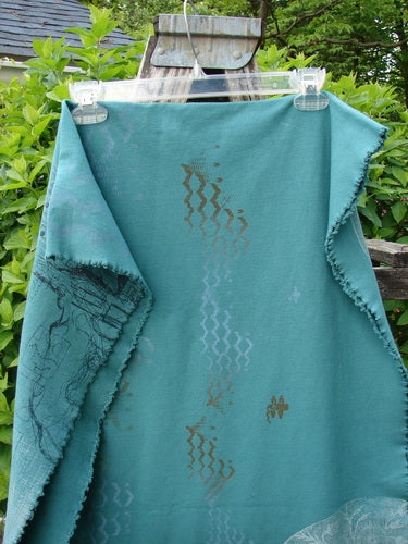 Barclay Heavy Weight Organic Sweatshirt Art Wrap Moon Garden Emerald OSFA displayed outdoors on a wooden frame, showcasing textured teal fabric with wavy zig-zag patterns and decorative motifs.