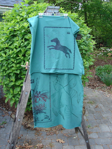 Barclay Heavy Weight Organic Sweatshirt Blanket Pony Garden Emerald OSFA draped on a wooden ladder, showcasing a horse silhouette on the top and floral designs on the bottom, set outdoors.