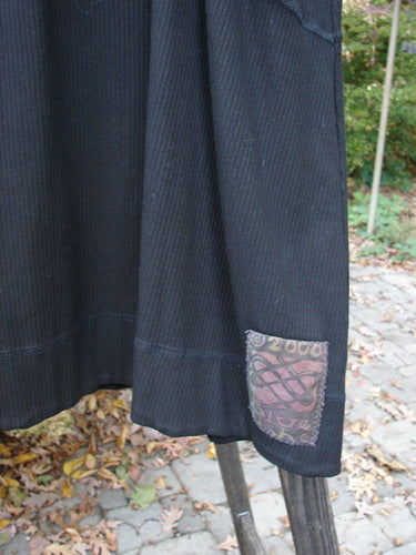 Close-up of the 2000 Rayon Lycra Rib Crossroad Pullover Unpainted Black Size 2, showcasing its V-neckline with exterior crisscross stitchery and A-line shape, highlighting the fabric's forgiving drape and bounce.