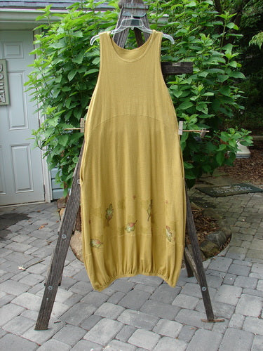 2000 Cotton Hemp Libby Jumper Falling Leaf Gold Altered Size 1 displayed on a wooden rack, showcasing a sophisticated drape, bubbled shape, and elastic hemline with two side pockets.