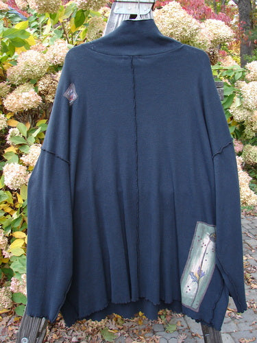Barclay Patched Thermal Reverse Stitch Big Square Tunic Nature Black Size 3 displayed on a hanger, featuring a floppy turtleneck, exterior center seams, drop shoulders, and painted nature-themed patches.