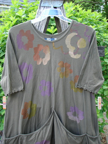 Barclay Quad Pocket Tie Back Tunic Dress Simple Floral Mushroom Size 0 features elbow-length sleeves, a rounded neckline, and quad pockets. The dress displays a scattered abstract floral pattern against an olive-green backdrop.