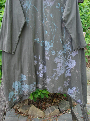 Barclay Three Quarter Sleeve Color Wheel Tunic Falling Floral Black Sand Size 0, featuring an asymmetric hem and floral patterns, draped over a wooden bench outdoors, showcasing unique design and individuality.