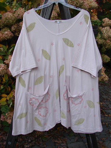 Barclay Double Draw Center Vent Tunic Top Leaf Pink Tile Size 2, featuring pink flower patterns, wide sleeves, two exterior pockets, and a flouncy lower skirt with a rounded hemline.