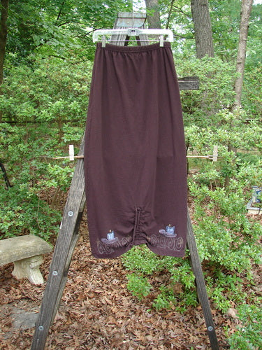 1999 Winter Skirt Candle Deep Burgundy Size 0 displayed on a wooden ladder, showcasing its pegged lower shape, scooped front hemline, and drawcord back, emphasizing its unique, tailored design.
