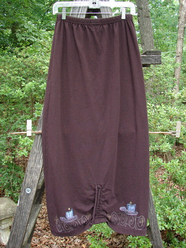 1999 Winter Skirt Candle Deep Burgundy Size 0 displayed on a wooden ladder, showcasing its unique scooped front hemline and pegged lower shape with a drawcord back.