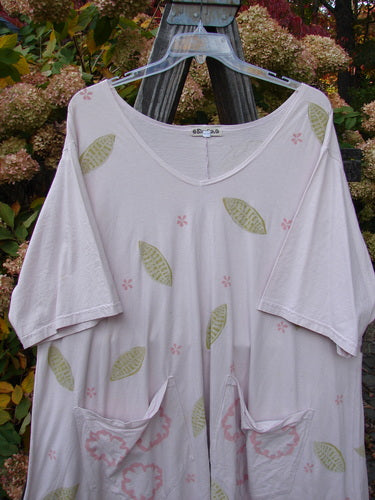 Barclay Double Draw Center Vent Tunic Top Leaf Pink Tile Size 2 displayed on an outdoor swing, featuring a rounded neckline, wide sleeves, and leaf-themed paint with exterior pockets and a flouncy lower skirt.