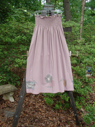 1995 Smocked Skirt Garden Patio Rose Size 2 hanging on a rack, showcasing its flowingly full hip measurements and sweet tiny ruffled top, perfect for vintage collectors.