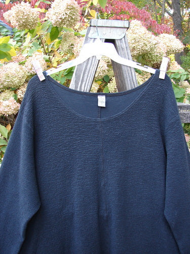 Barclay Crepe Hi Low Top Unpainted Black Size 2 displayed on a clothes rack, showcasing its long cozy sleeves, wider rounded neckline, and upward curved front hemline.