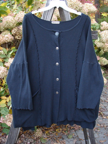 Barclay Thermal Curl Pocket Cardigan Unpainted Black Size 3 displayed on a clothes rack, showcasing its dolman sleeves, full button front, and two exterior pockets.