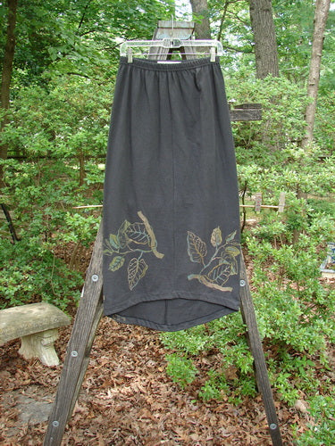 1998 Botanicals Corolla Skirt Leaf Vine Raven Size 1 displayed on a wooden ladder, highlighting its full elastic waistband, upward scooped front hemline, and botanical leaf vine design.