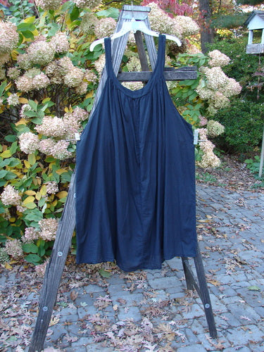Barclay Batiste Banded Collar Slip Dress displayed on a wooden easel, showcasing its deep rounded neckline, paneled shoulder straps, and swingy lower hemline.
