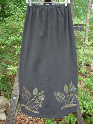 1998 Botanicals Corolla Skirt Leaf Vine Raven Size 1, featuring a long black skirt with a floral design, full elastic waistband, and upward scooped front hemline, made from organic cotton.