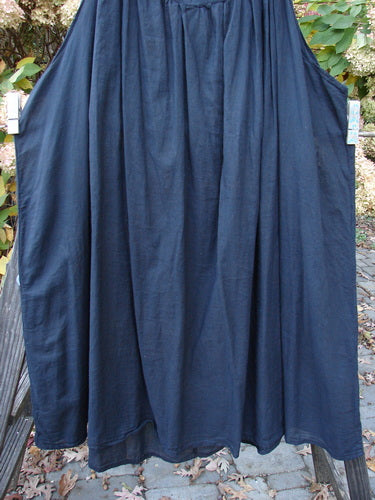 Barclay Batiste Banded Collar Slip Dress hangs on a rack, showcasing its super deep wide rounded neckline and mega gathered fabric, perfect for a breezy summer day.