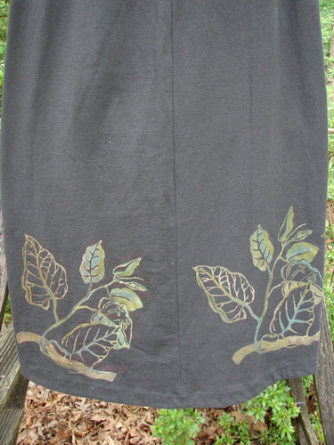 1998 Botanicals Corolla Skirt Leaf Vine Raven Size 1: A skirt with painted leaf designs, featuring an upward scooped front hemline and a full elastic waistband, made from organic cotton.
