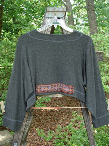 2000 Patched Rayon Lycra Rib Overtop Charcoal Heather Size 1 displayed on a wooden hanger, showcasing a dramatic upward scooping hemline and exterior stitchery with Celtic-themed painted patches.