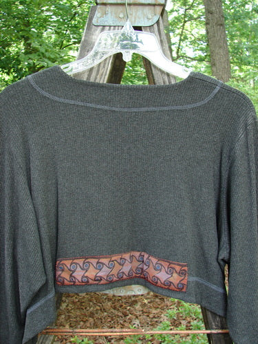 2000 Patched Rayon Lycra Rib Overtop Charcoal Heather Size 1 displayed on a swing, showcasing its dramatic upward scooping hemline, exterior stitchery, and Celtic-themed painted patches.