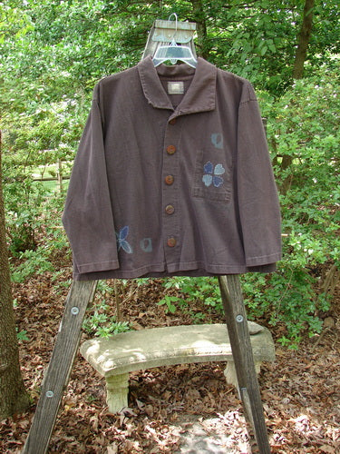 1999 Hidden Pocket Jacket Clover Heart Current Size 0, displayed on a wooden ladder, featuring oversized buttons with clover heart designs, a signature patch, and an adjustable collar.