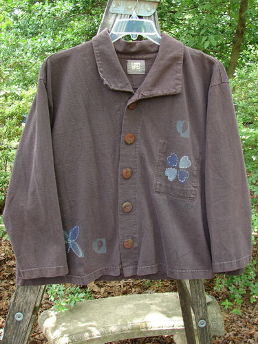1999 Hidden Pocket Jacket Clover Heart Current Size 0 featuring blue flower designs, adjustable collar, oversized blue buttons with clover hearts, and a bright rear patch.