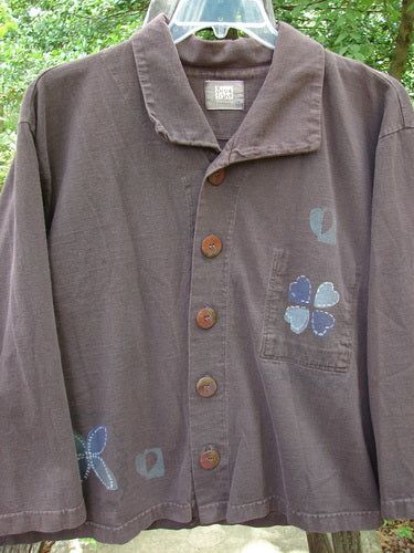 1999 Hidden Pocket Jacket Clover Heart Current Size 0 featuring a patch with a four-leaf clover and flower, oversized painted buttons, and a hidden pocket. Slightly faded collar.