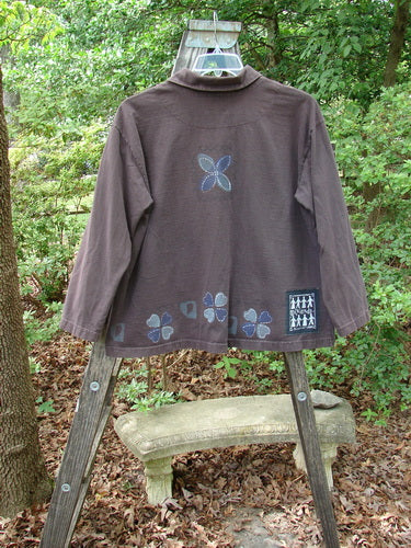 1999 Hidden Pocket Jacket Clover Heart Current Size 0 displayed on a wooden ladder, showcasing its drop shoulders, oversized buttons with clover heart design, adjustable collar, and bright Blue Fish patch.