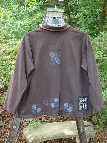 1999 Hidden Pocket Jacket Clover Heart Current Size 0: Brown jacket with a flower design, featuring oversized blue buttons painted with clover hearts and a blue fish patch on the rear bottom.