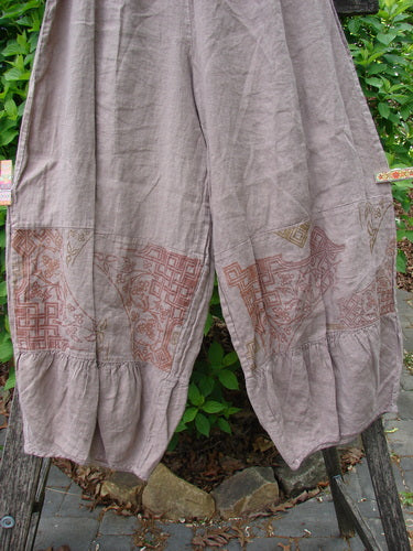 Barclay Linen Meadow Pant Celtic Vine Stone Oriel Size 0: Wide-leg pants with geometric and floral motifs, ruffled hems, and gathered panels, draped outdoors against green foliage.
