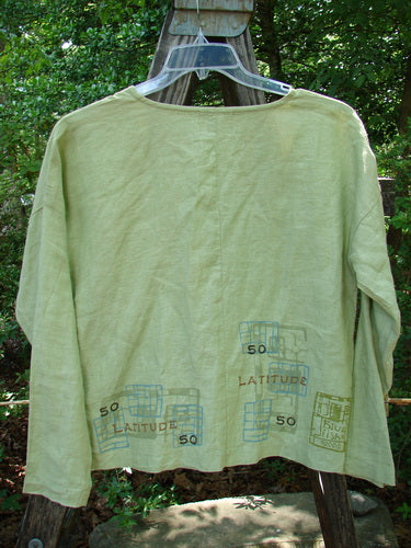 2000 Cross Dye Linen East Side Jacket Latitude Celery Size 0 displayed on an outdoor swing, showcasing its boxy shape, ceramic buttons, and vented sides.