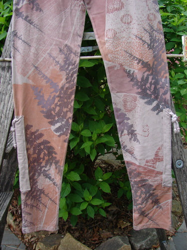 Barclay Cotton Lycra Side Gather Legging Forest Moon Oriel Size 0, displayed on a wooden bench, features an abstract foliage print in earth tones, with drawcords on tapered legs, showcasing a vintage aesthetic.