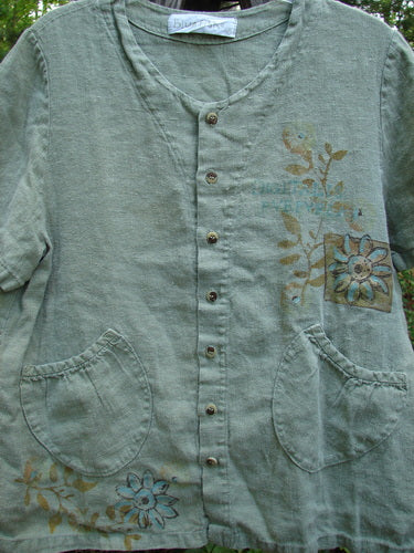 1998 Botanicals Robin's Top Daisy Elm Size 0: Close-up of heavy-weight linen shirt with daisy and garden-themed paint, featuring dual front pockets, tiny buttons, and an A-line shape.