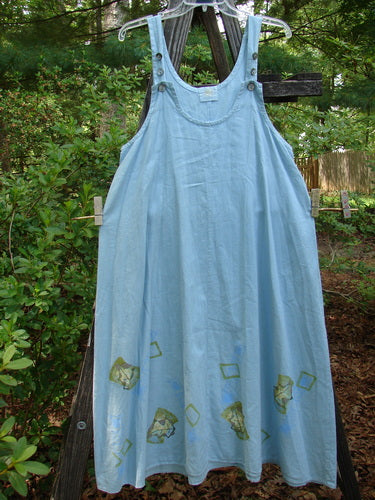 2000 Strappy Jumper Leaf Path Blue Jet Size 1 displayed on a wooden cross, showcasing its large A-line flare, pearl buttons, and bright leaf path hemline.