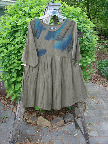 Barclay Linen Two Pocket Dolly Dress Brush Paint Wood Size 0, featuring a loose fit, elbow-length sleeves, dropped waist, abstract brush-stroke patterns, and dual exterior pockets, displayed on a wooden stepladder.