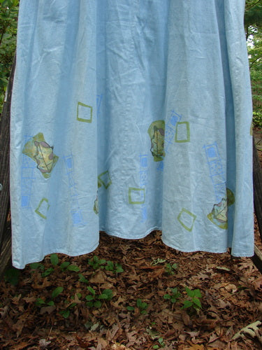 2000 Strappy Jumper Leaf Path Blue Jet Size 1 featuring green square and leaf patterns, adjustable pearl buttons, and a flared A-line shape with a scooped neckline.