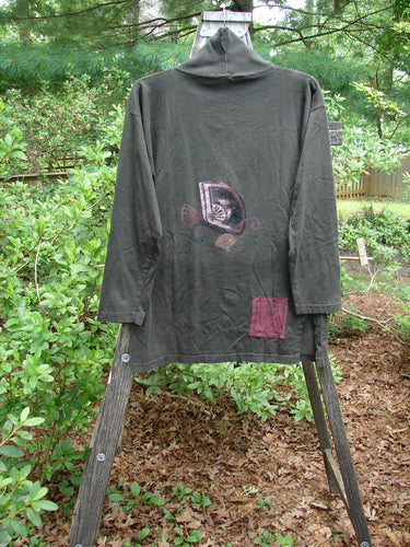 1994 Long Sleeved Vented Turtleneck Top Fan Edo Black Altered Size 1 displayed on a rack, featuring a cartoon design and a blue fish patch, highlighting its unique drop shoulders and vented sides.