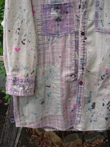 Magnolia Pearl Surfside Shirt: A white-and-lavender plaid flannel with vibrant paint splatters, showcasing generous patching, button cuffs, a single breast pocket, and unique hemline, embodying artistic flair and individuality.