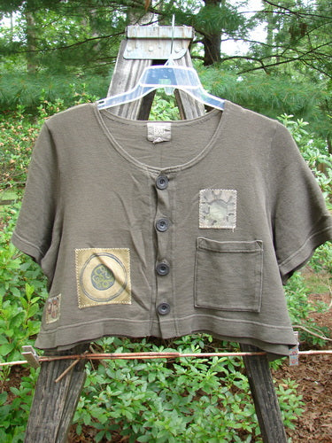 2000 Patched Recycle Jacket Science Bark Size 0, featuring a feminine rounded neckline, flared hemline, front squared drop pocket, dark recycled buttons, and colorful bio-themed patches, displayed on a hanger.