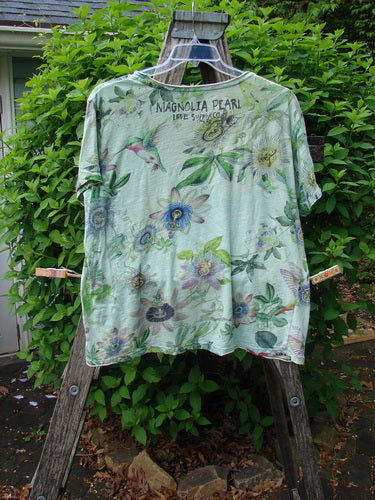 Magnolia Pearl Cotton Jersey Boyfriend Tee Passion Flower Big Sky OSFA displayed on a wooden ladder, featuring botanical illustrations and the words “MAGNOLIA PEARL LIVE SLOW CO.” across the upper back.