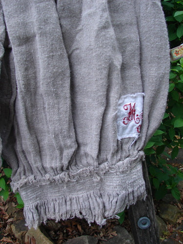 Magnolia Pearl Homespun Linen Crop Smocked Bloomer draped on a wooden bench, showcasing gathered hems, full smocked waistline, and the signature love patch at the rear center with a scripted M.P. patch.