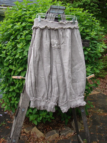 Magnolia Pearl Homespun Linen Crop Smocked Bloomer Flaxen OSFA displayed outdoors, featuring a smocked waistband, ruffled cuffs, signature love patch, and scripted M.P. patch, capturing vintage elegance in natural linen.