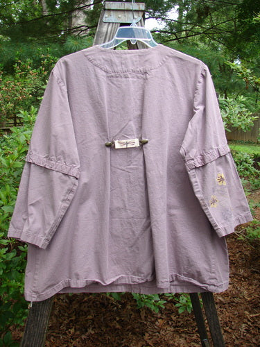 2000 Parachute Camper Jacket Florals Pale Purple Size 0 displayed on a swing, showcasing its versatile snap line, widening A-line shape, and four painted front pockets.