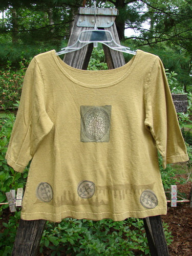 2000 Cotton Hemp Theo Top Center Gold Size 0 displayed on a swinger, showcasing three-quarter sleeves, a rounded neckline, and an A-line shape, part of the Resort Collection from Bluefishfinder.com.