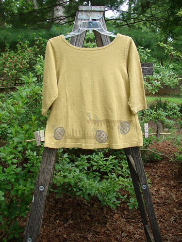 2000 Cotton Hemp Theo Top Center Gold Size 0 displayed on a wooden easel, featuring three-quarter sleeves, a rounded neckline, and a classic resort science-themed paint.