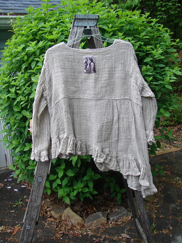 Magnolia Pearl Fisherman's Weave Asymmetrical Ruffle Jacket OSFA displayed on a weathered ladder, highlighting its ruffled hem, oversized pearl buttons, and signature Magnolia Pearl patch at the back neckline.