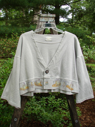 1999 Interlock Solstice Jacket Candle Blue Horizon Size 0, featuring a cropped length, deep V-neckline, two-button front, drop shoulders, wide belled sleeves, and holiday-inspired candle design.