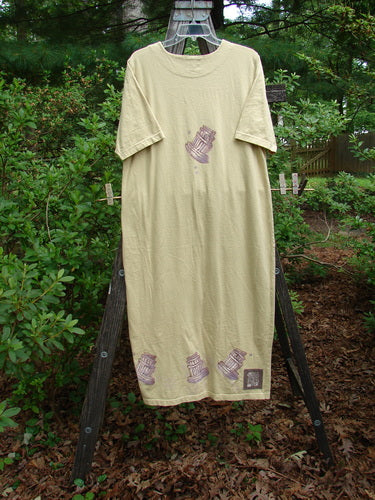 1999 Straight Dress Sugar Bowl Plantain Altered Size 1 on a wooden clothes rack, showcasing its organic cotton fabric with rounded side pockets, a paneled neckline, and a signature Blue Fish patch.