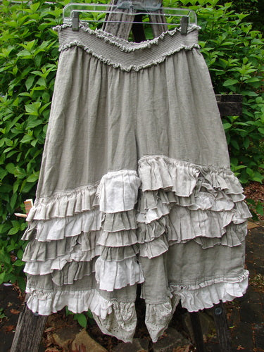 Magnolia Pearl Linen Eiffel Tower Bloomer Flaxen OSFA: A lightweight, tiered skirt with a smocked waistband and layered ruffles, displayed on a hanger against a leafy background, reflecting Bluefishfinder's vintage-inspired style.