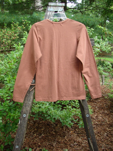 1997 Cotton Lycra Long Sleeved Layering Top Unpainted Copper Size 1 displayed on a wooden ladder, showcasing its rounded shallow neckline, tapering waist, and slight lower flair.