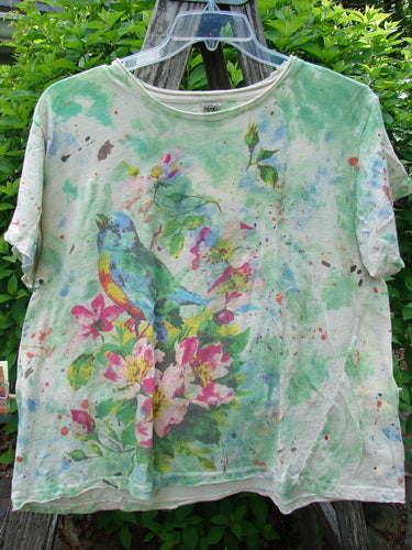 Magnolia Pearl Cotton Jersey Boyfriend Tee Songbird Floral OSFA, featuring a colorful songbird and floral print, hung outdoors on a ladder, showcasing its lightweight, distressed design with finished edges.