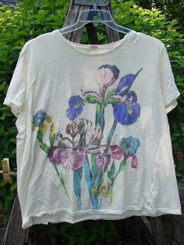 Magnolia Pearl Cotton Jersey Boyfriend Tee Iris Garden OSFA, featuring a vibrant iris flower print, displayed outdoors on a hanger, highlighting its drapey, super soft texture and unique distressed detailing.